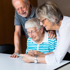 Wall Mural - Three elderly persons using smart phone