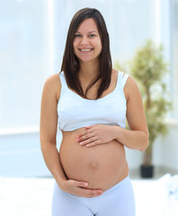 Wall Mural - portrait of young pregnant woman on a light background.