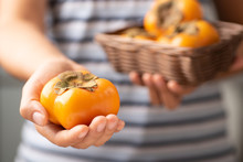 Ripe Persimmon Fruit Holding By Woman Hand