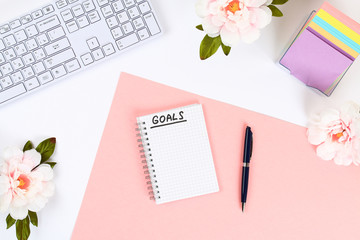 write a goal for the new year 2010 in a white notebook on a white desktop next to a coffee mug and a