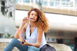 © mimagephotos - female university student sitting outside with book and pen