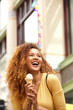 © mimagephotos - young woman eating ice cream in the city