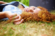 © mimagephotos - happy young woman lying in grass in park