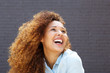 © mimagephotos - Close up beautiful young woman with curly hair smiling and looking up
