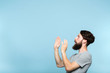 © golubovy - man looking sideways and is intimidated or scared by smth on the left. free space for advertisement. portrait of a bearded guy on blue background.