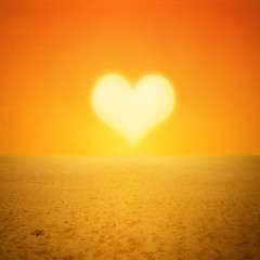 Sunset sun heart shape in desert or beach landscape with footprints