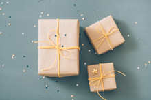 Presents Wrapping And Packaging. Holiday Traditions And Handcraft. Three Gift Boxes In Craft Paper And Tied With Yellow Twine On Blue Background.