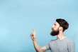© golubovy - thoughtful man reaching and wanting to press virtual button on the left. free space for advertisement or text. portrait of a bearded guy on blue background.