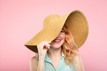 Wall Mural - summer vacation tours concept. young pretty woman in a big sunhat ready to go to the beach. cute stylish girl portrait on pink background.