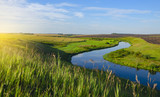 Beautiful view of river curve,green and yellow fields illuminated by the warm light of rising sun.