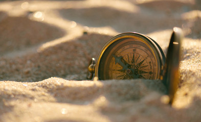 Wall Mural - Old vintage compass on the sand beach. Travel navigation concept .