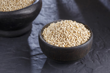 Wall Mural - Quinoa grains with spoon and bowl on black background