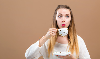 Young woman drinking coffee on a brown background