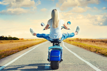  Girl biker riding a motorbike on an asphalt road.