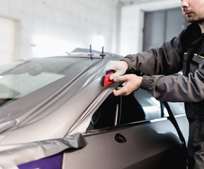 Wall Mural - Car wrapping specialist putting vinyl foil or film on car. Selective focus.