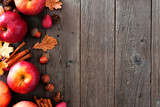 Autumn side border of apples and fall ingredients on a rustic wood background with copy space