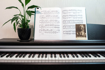 2018.09.18, Moscow, Russia. An open book of sheet music on the piano. A composition of the sheet music, flower, vintage postcard with Chopin and the piano keyboard.
