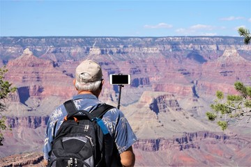 a male traveler with backpack taking the photo with smartphone of beautiful view at grand canyon nat