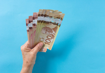 Paper notes from Canada. Dollar. Top view of old woman's hand handling bills.