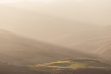 Sunrays coming over a valley and a hill