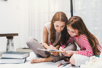 Family Happy Mother and daughter drawing with colorful pencils on book in bedroom