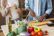 Black couple preparing healthy vegetable salad in kitchen