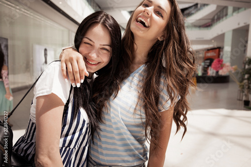 Two Young Pretty Dark Haired Girls Wearing Casual Outfit Hug Each