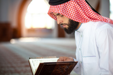 Poster - Ethnic man reading Koran and praying in mosque