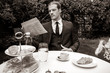 Man dressed in suit drinks esperesso at a cafe table