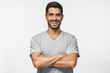 © Damir Khabirov - Portrait of laughing handsome man in blue t-shirt standing with crossed arms isolated on grey background
