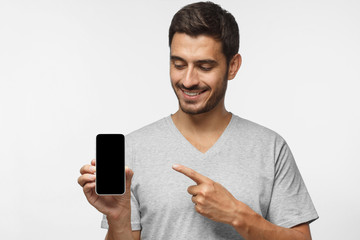 Wall Mural - portrait of happy man demonstrating blank smartphone and pointing to empty blank screen with smile. 