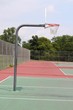 A side view of the basketball hoop on the outdoor court.