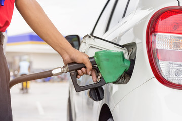 Pumping gas at gas pump. Closeup of man pumping gasoline fuel in car at gas station