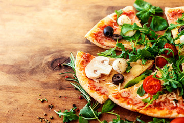 Hot pizza slice with Pepperoni, tomatoes, melting cheese on a rustic wooden table close up. Copy space.