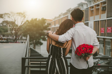 Man holding flowers behind The surprise for his sweetheart.