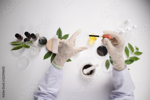 Cuadros en Lienzo Scientist hand holding green leaf in glass cuvette on laboratory