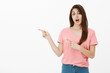© Cookie Studio - Girl asks if she can leave for second. Portrait of casual carefree good-looking woman in pink t-shirt, pointing left with index fingers and asking question, standing with opened mouth