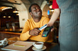 © pressmaster - Contemporary young man paying for his drink through contactless payment app in his smartphone