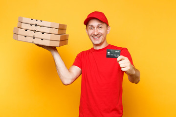 Wall Mural - Delivery man in red cap t-shirt giving food order pizza boxes isolated on yellow background. Male employee pizzaman courier holding italian pizza in cardboard flatbox credit bank card. Service concept