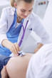 © lenets_tan - Young woman doctor with stethoscope speaking with pregnant woman at hospital.