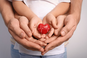 Sticker - Family holding small red heart in hands together, closeup