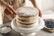 Woman Decorating Delicious Cake With Fresh Cream On Stand. Homemade Pastry