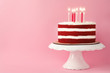 © New Africa - Delicious homemade red velvet cake with candles on pink background. Space for text