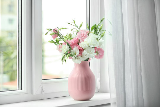 Vase with beautiful flowers on window sill