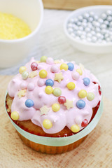 Poster - Woman prepares muffins decorated with cream and sprinkles.