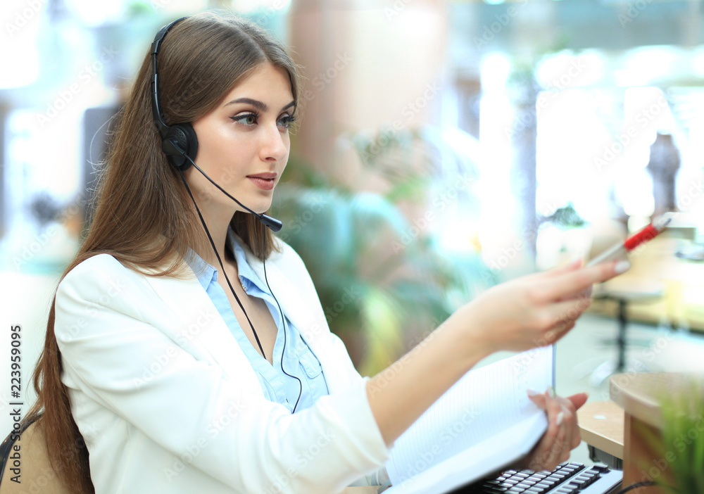 Smiling call center agent pointing at something on computer screen in ...