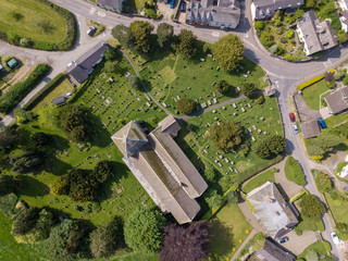 Wall Mural - Aerial view above a Church cemetery and houses in an old British village in the countryside. Warm colours give a homely effect.