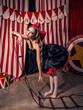 Beautiful girl with doll face with red bow is tired to climb the ladder in dark circus