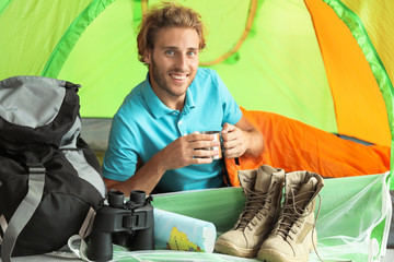 Poster - Young man in sleeping bag with mug inside of tent