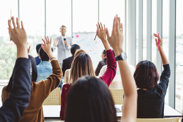 Group of business people raise hands up to agree with speaker in the meeting room seminar